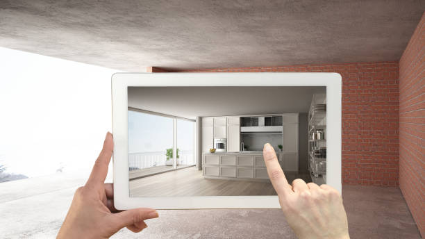 istock Augmented reality concept. Hand holding tablet with AR application used to simulate furniture and design products in interior construction site, classic kitchen with island 1136188733