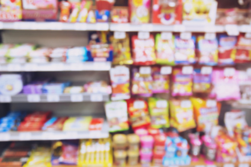 blur photo background of snacks and consumer product colorful in supermarket shop shelf. Mini-mart shopping convenience stores are a new alternative for the urban people concept