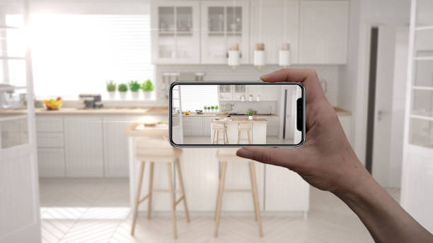 istock Hand holding smart phone, AR application, simulate furniture and interior design products in real home, architect designer concept, blur background, modern scandinavian wooden kitchen 1136189704