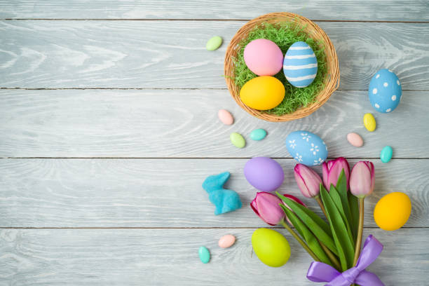 istock Easter holiday background with easter eggs in basket and tulip flowers on wooden table. 1136190433
