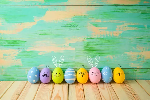 Photo of Easter eggs decorations on wooden table over colorful background