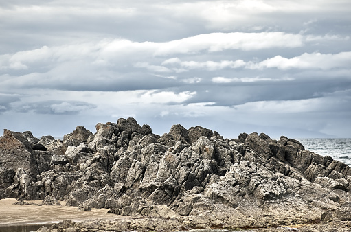 Rocky mountain coast, Kunashir island, Stolbchaty cape, cloudy gray gloomy sky.