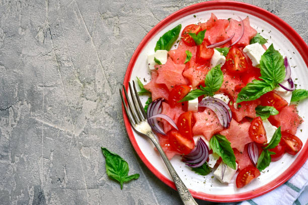 Watermelon salad with tomato, feta cheese, red onion and basil stock photo