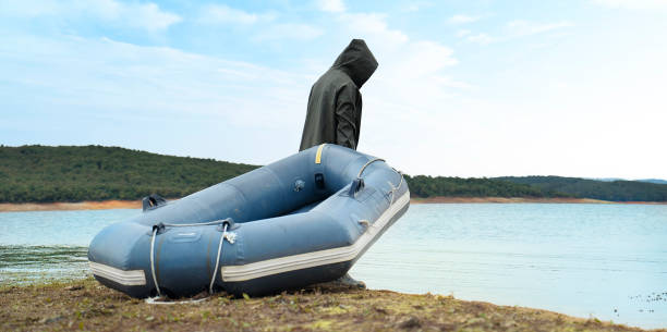 White inflatable motorboat with a red canopy is anchored to a buoy on calm open water, featuring padded seats and a covered console, viewed from the rear