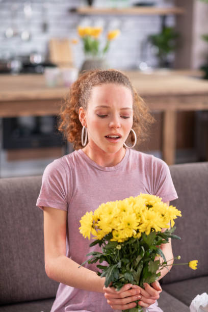 istock Miserable curly-haired woman sneezing while carrying bouquet 1136200279