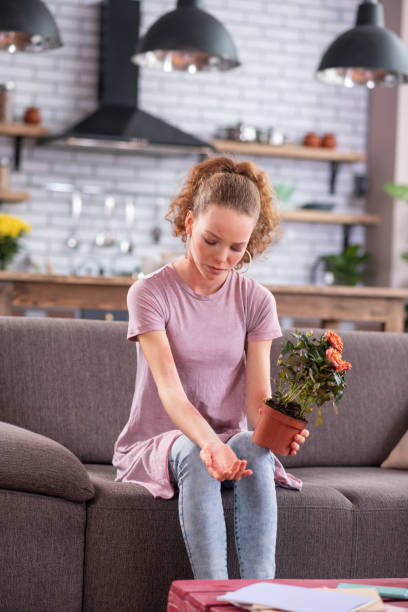 istock Miserable ginger young lady sitting on grey couch with pot 1136200415
