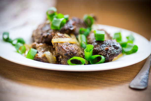 fried liver with onions in a plate on a wooden table