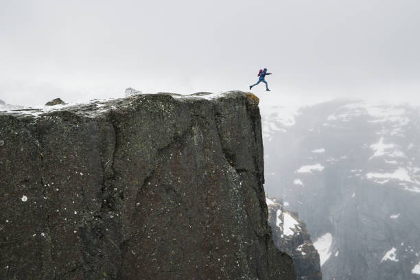 istock Lonely man jumping from high edge of cliff. Free falling. 1136205328