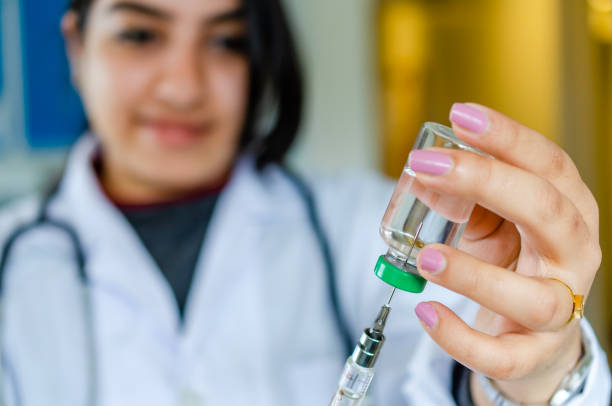 Woman doctor drawing vaccine medicine in syringe stock photo
