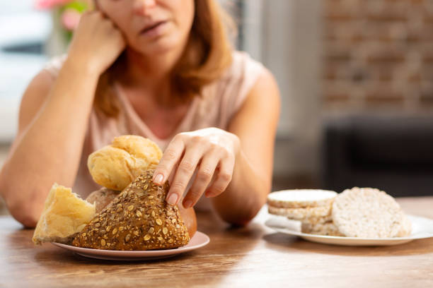 woman allergic to gluten taking little bun with seeds - gluten allergy imagens e fotografias de stock
