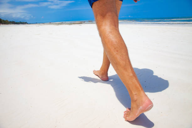 istock Mature man Walking Barefoot on White beach Sand 1136208330
