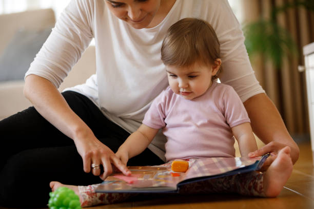 mère et fille lisant le livre ensemble - baby book toddler reading photos et images de collection