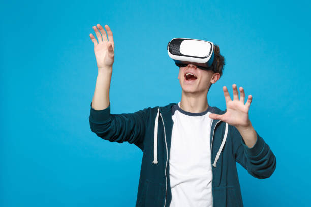 istock Amazed young man in headset touch something like push click on button, pointing at floating virtual screen isolated on blue background. People sincere emotions, lifestyle concept. Mock up copy space. 1136214717