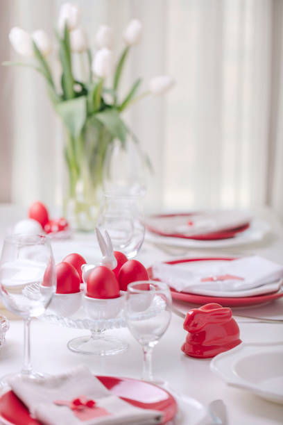 istock Happy easter. Decor and table setting of the Easter table is a vase with white tulips and dishes of red and white color. Easter colored eggs with white polka dots. 1136221104