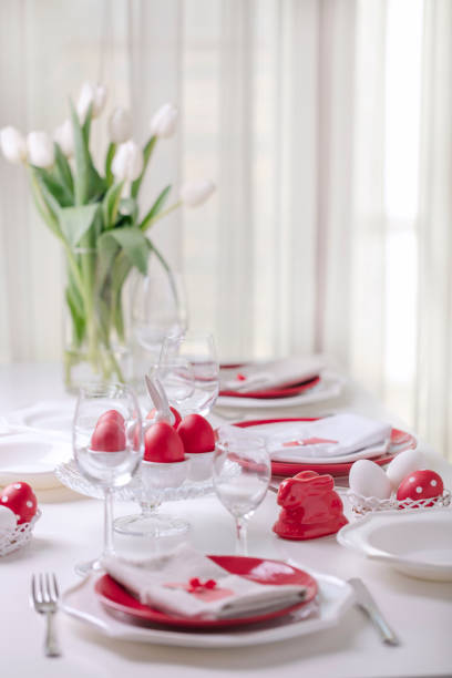 istock Happy easter. Decor and table setting of the Easter table is a vase with white tulips and dishes of red and white color. Easter colored eggs with white polka dots. 1136221105