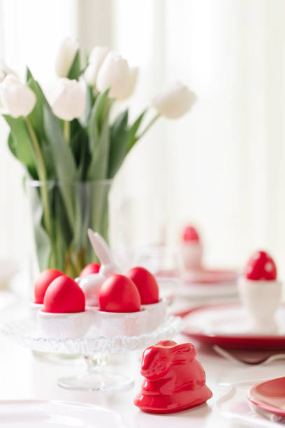 istock Happy easter. Decor and table setting of the Easter table is a vase with white tulips and dishes of red and white color. Easter colored eggs with white polka dots. 1136221108