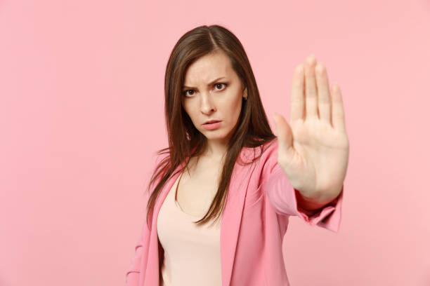 Portrait of disconcerted young woman in jacket looking camera, showing stop gesture with palm isolated on pastel pink wall background. People sincere emotions, lifestyle concept. Mock up copy space retrato de la mujer joven desconcertada en la chaqueta que mira la cámara, mostrando gesto de parada con la palma aislada en el fondo de pared rosa pastel. personas emociones sinceras, concepto de estilo de vida. maqueta de espacio de copia.