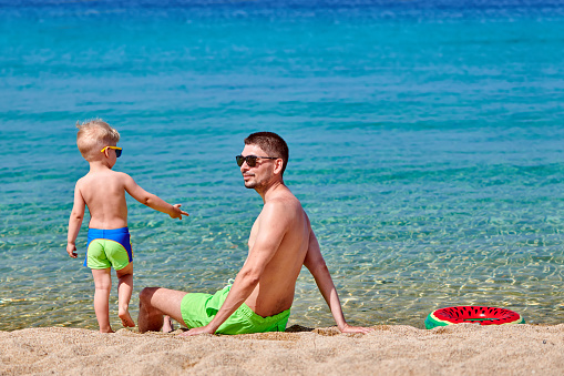 Two year old toddler boy on beach with father