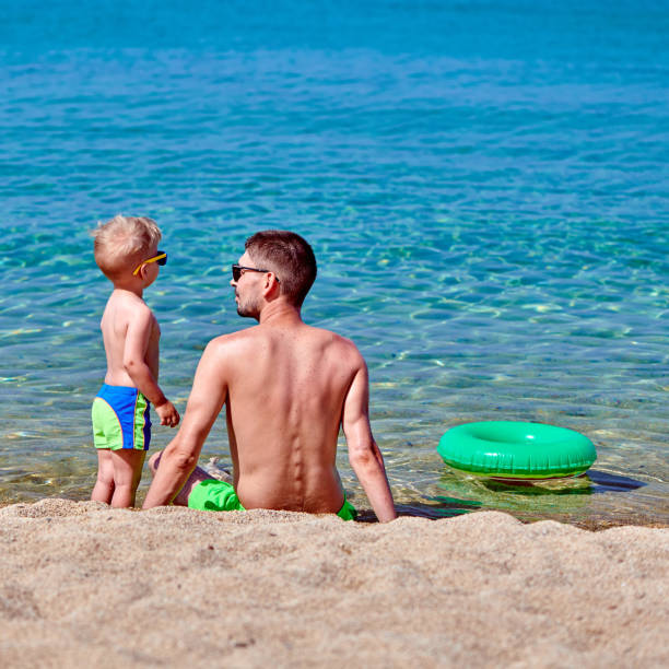 Two year old toddler boy on beach with father