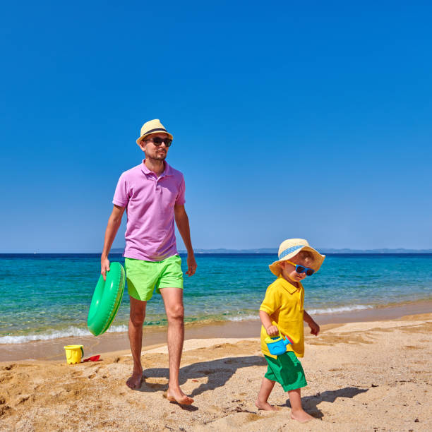 istock Toddler boy walking on beach with father 1136229197