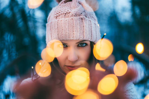 Portrait of a young beautiful woman wrapped in Christmas lights in the snow