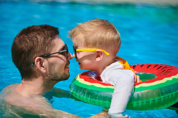 Toddler boy in resort pool with father