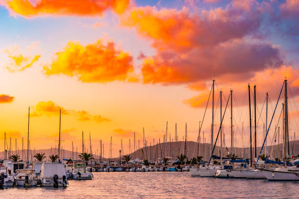 Sunset at the harbor in Alghero, Sardinia, Italy. Beautiful purple sunset over boats in the harbor of famous old town of Sardinia.