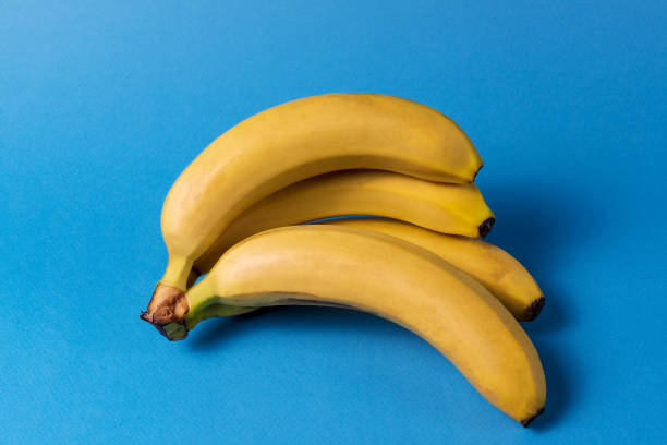 istock Minimalism style. pattern with bunch of yellow ripe banana fruit over blue background. 1136237644