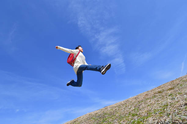 istock Japanese elementary school girl jumping in the blue sky 1136238879