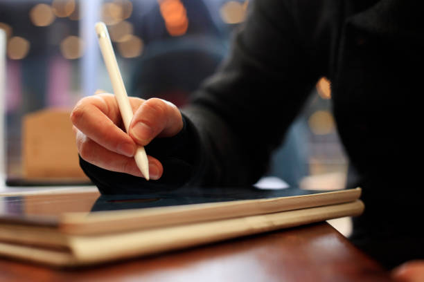 Close up of male hand using digital pen writing on digital tablet screen
