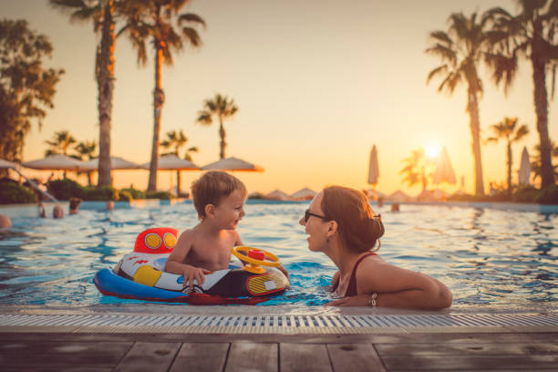 child with mother in swimming pool, holiday resort - floating on water fotos imagens e fotografias de stock