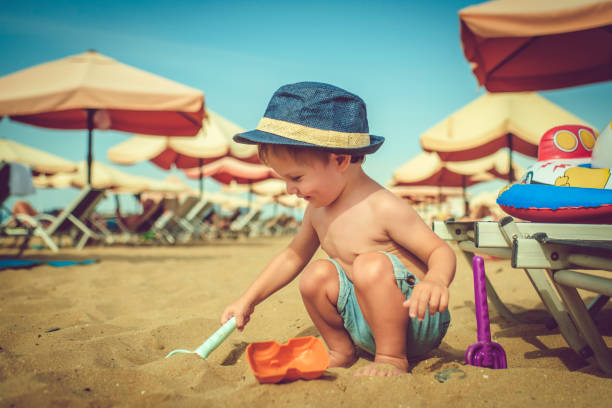 Cute happy child on the beach playing with sand Little boy on the beach playing with sand shovel in sand stock pictures, royalty-free photos & images