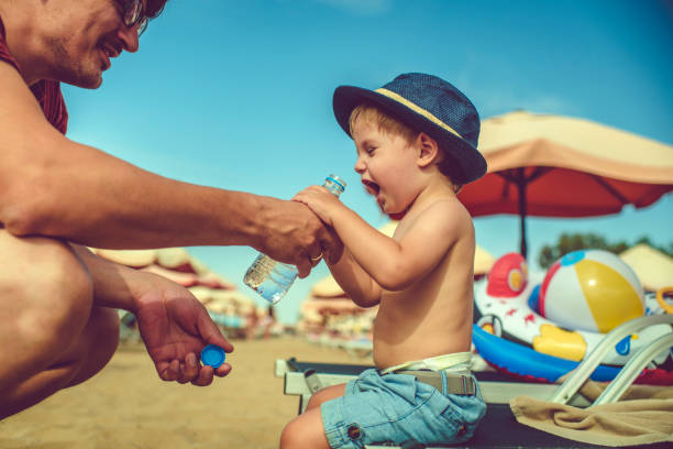 istock Father helping his son to drink water on the beach 1136247301