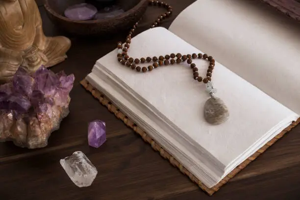 Open leatherbound journal or notebook surrounded by crystals on a wooden surface