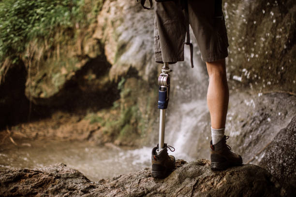 istock Guy with prosthetic leg standing on rock by waterfall 1136258133