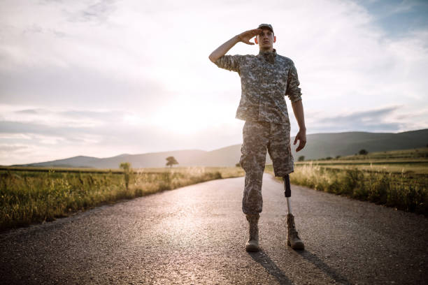 istock Brave soldier with prosthetic leg saluting on road 1136258159