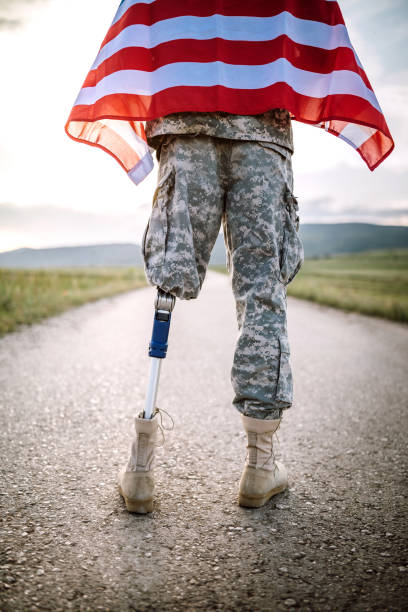 istock Amputee soldier with American flag on road 1136259173