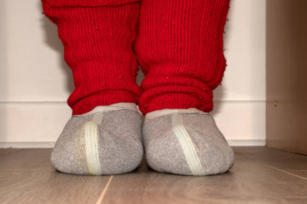 istock Red knitted socks and woolen slippers on the feet 1136260474