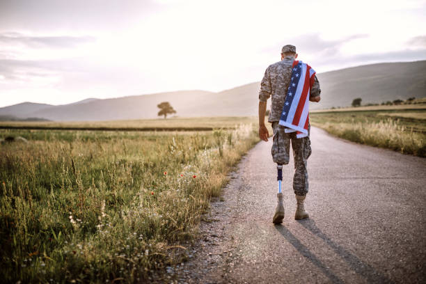 istock Amputee soldier with American flag on road 1136260675