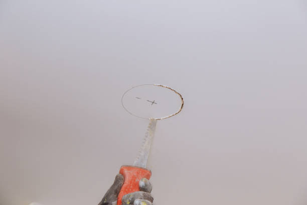 Handsaw cutting to cut a hole in the ceiling to put electrician ecological light