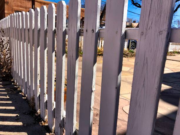 istock White picket fence with adobe house and blue sky in background 1136266705
