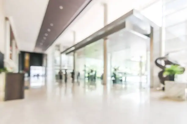 Photo of Blur hotel or office lobby background interior view toward reception hall, modern luxury white room space with blurry corridor and building glass wall window