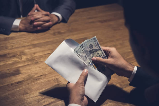 istock Businessman counting money in the envelope just given by his partner 1136269502