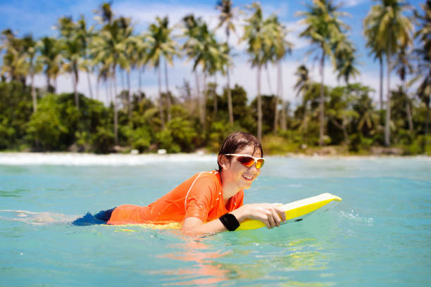 istock Child surfing on tropical beach. Surfer in ocean. 1136270586
