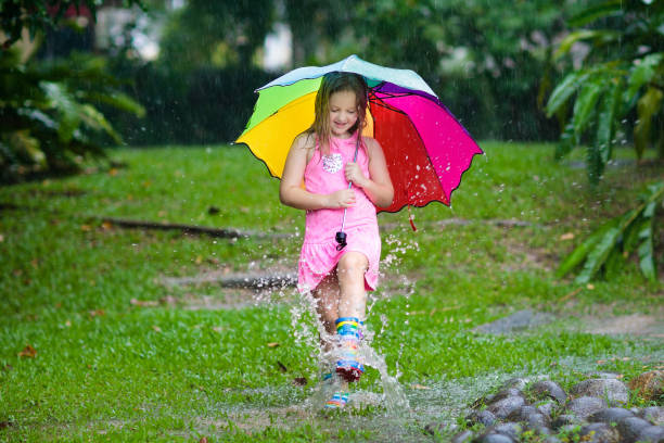 istock Kid with umbrella playing in summer rain. 1136271067