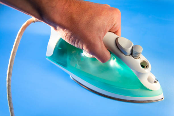 istock home laundry iron in a man's hand on a blue surface 1136271156