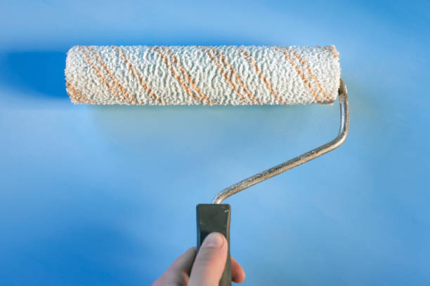 istock paint roller in male hand on blue background 1136271208