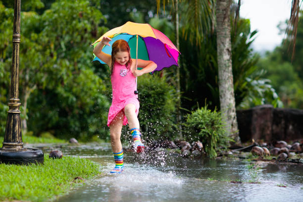 istock Kid with umbrella playing in summer rain. 1136274207
