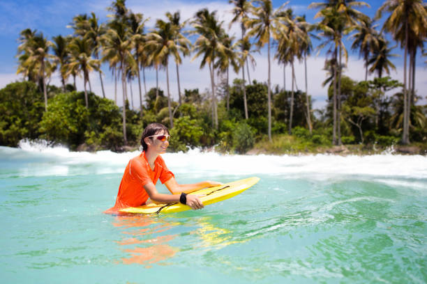 istock Child surfing on tropical beach. Surfer in ocean. 1136274392