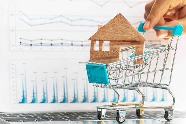 istock Hand push forward wooden house in trolley on laptop computer with report chart documents for property investment mortgage financial on online shopping or payment housing monthly installments credit. 1136287676